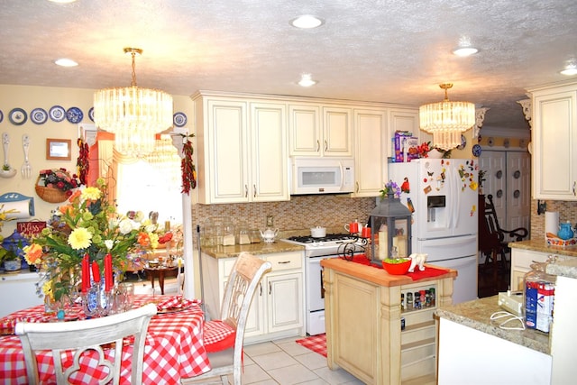 kitchen featuring white appliances, a chandelier, hanging light fixtures, and cream cabinetry