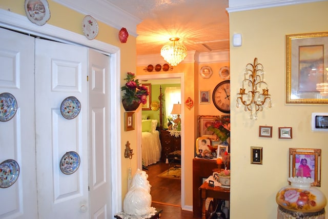 corridor featuring hardwood / wood-style flooring, crown molding, and an inviting chandelier