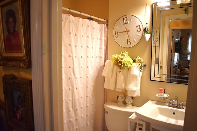 bathroom with walk in shower, sink, and toilet