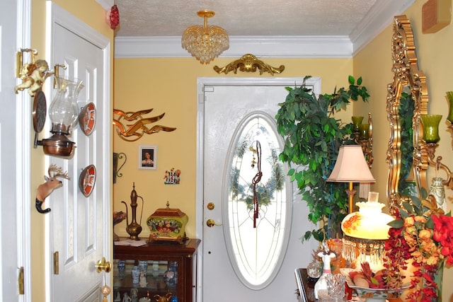 entryway with an inviting chandelier, ornamental molding, and a textured ceiling