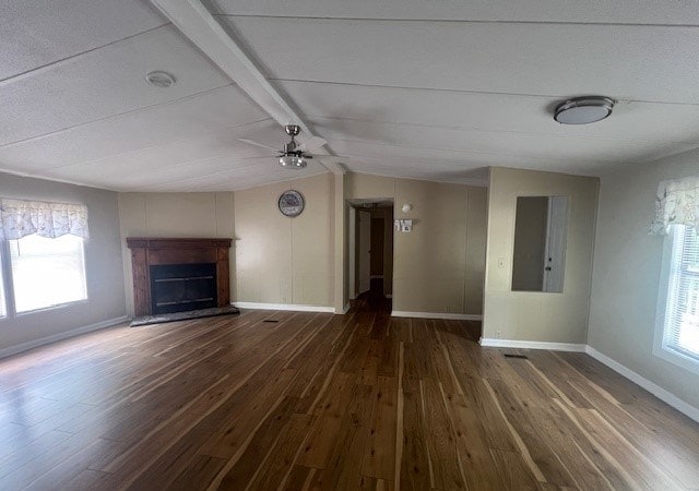 unfurnished living room with ceiling fan, plenty of natural light, dark hardwood / wood-style floors, and lofted ceiling with beams