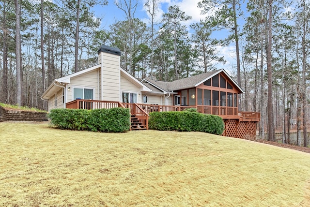 rear view of property with a deck, a sunroom, and a lawn