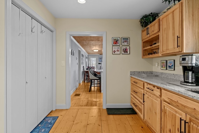 kitchen featuring light stone counters, light brown cabinets, and light wood-type flooring