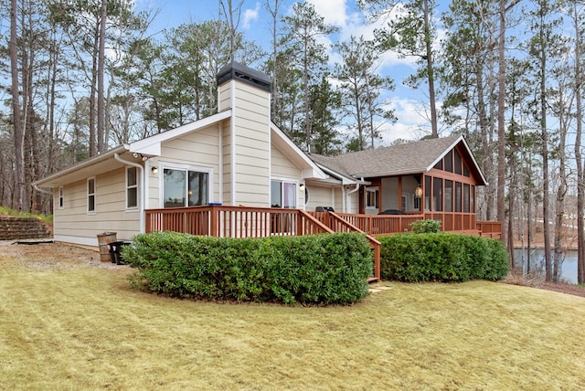 back of house with a sunroom, a deck, and a lawn