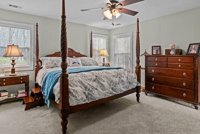 bedroom featuring multiple windows, light colored carpet, and ceiling fan