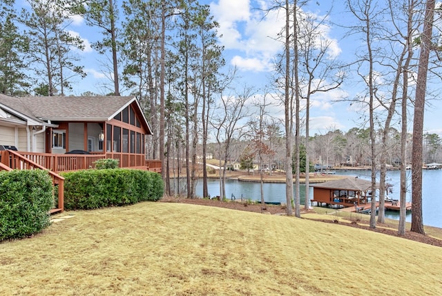 view of yard featuring a sunroom and a water view