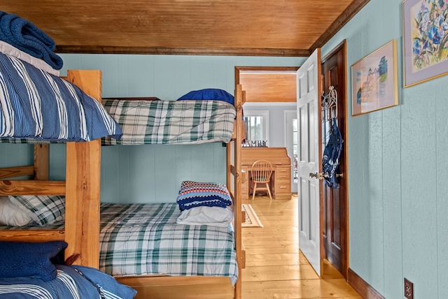 bedroom with wooden walls, wood ceiling, and light hardwood / wood-style floors