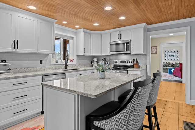 kitchen with white cabinetry, wooden ceiling, a breakfast bar, and appliances with stainless steel finishes