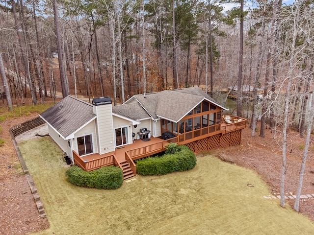 rear view of house featuring a lawn, a sunroom, and a deck