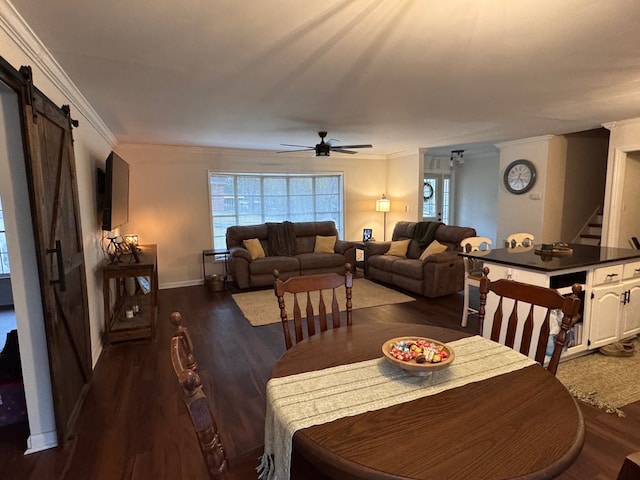 dining room with ceiling fan, a barn door, dark wood-type flooring, and ornamental molding