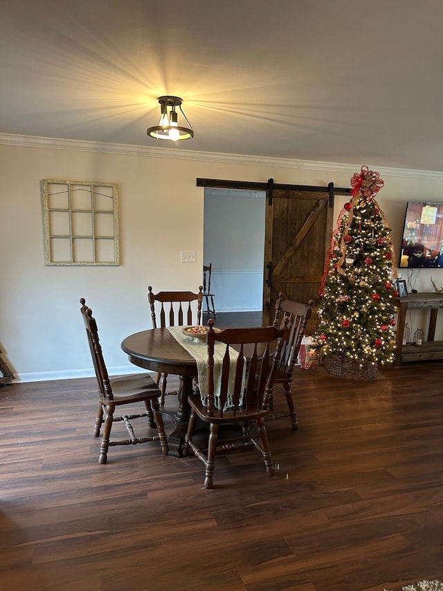 dining room with dark wood-type flooring, ornamental molding, and a barn door