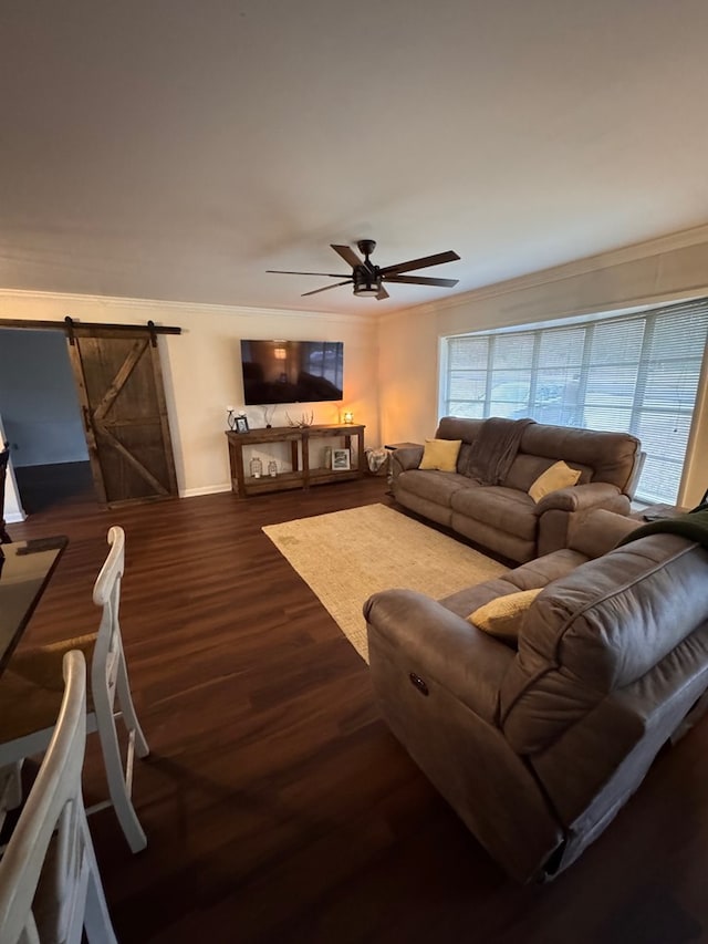 living room with ceiling fan, dark hardwood / wood-style flooring, crown molding, and a barn door