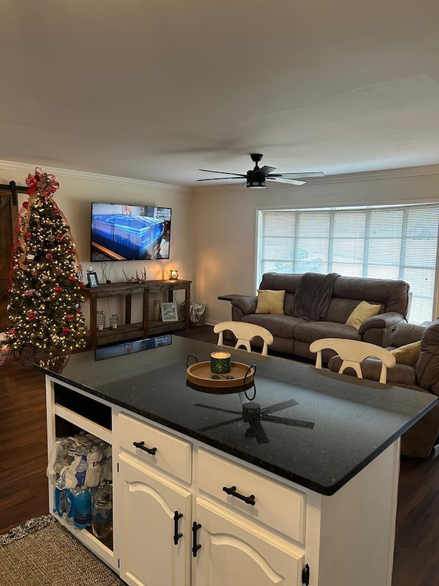 kitchen featuring white cabinets, dark wood-type flooring, dark stone countertops, ceiling fan, and crown molding