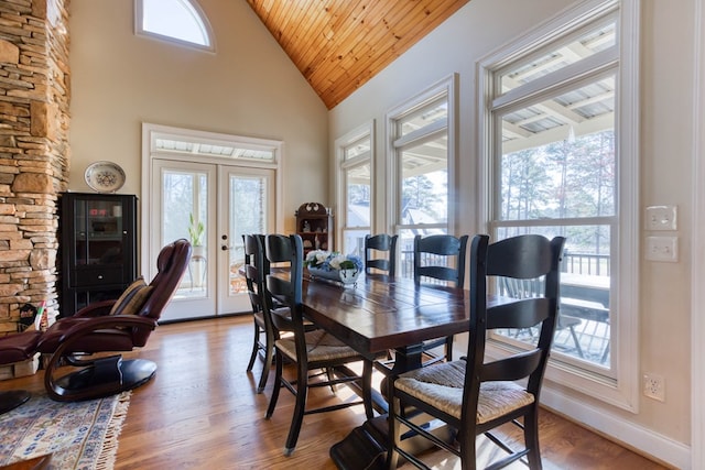 dining area featuring french doors, baseboards, high vaulted ceiling, and wood finished floors