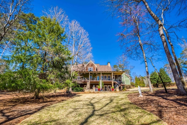 back of property featuring stairway, a yard, and a chimney