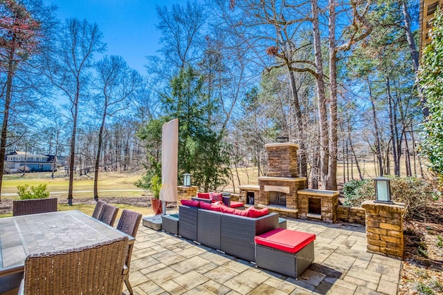 view of patio with an outdoor living space with a fireplace and outdoor dining area