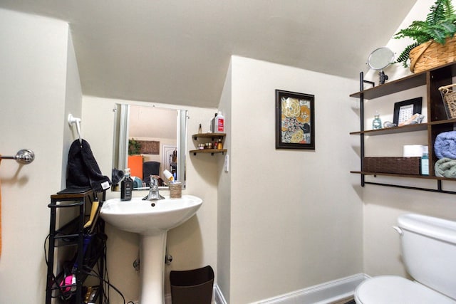 half bath with a sink, baseboards, and toilet