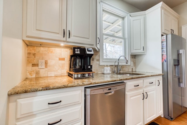 kitchen with white cabinets, tasteful backsplash, appliances with stainless steel finishes, and a sink