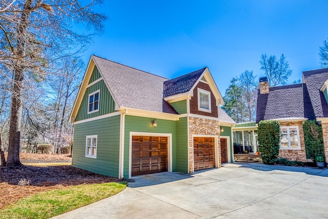 view of front facade with board and batten siding, a shingled roof, concrete driveway, a chimney, and a garage