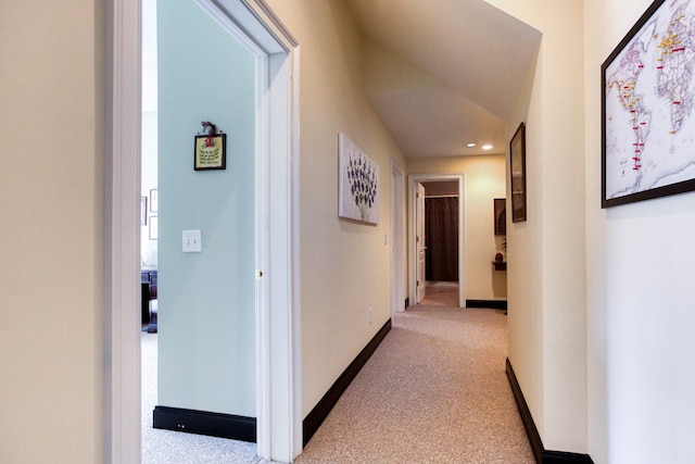 corridor featuring baseboards and light colored carpet