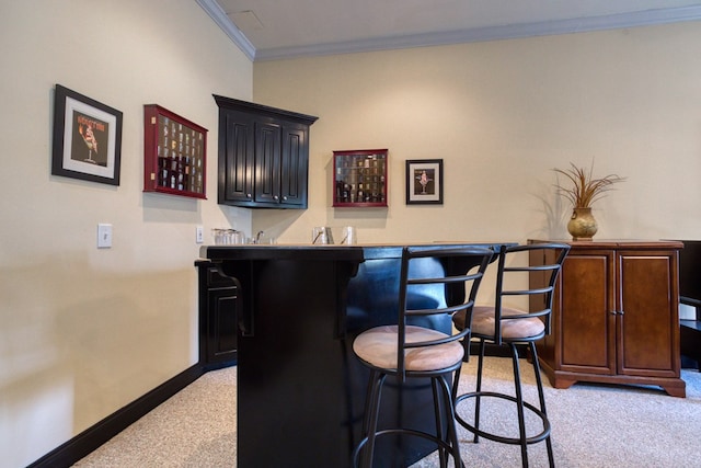 bar featuring light carpet, baseboards, indoor bar, and ornamental molding