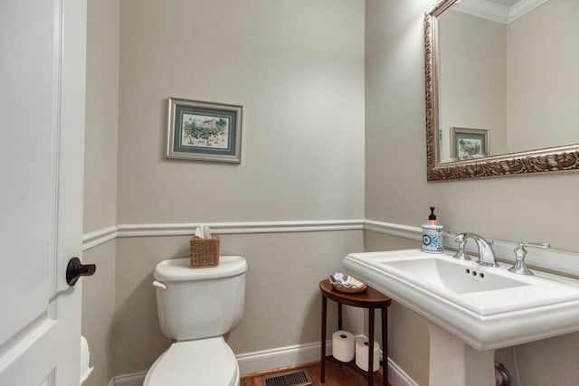 half bathroom featuring wood finished floors, baseboards, visible vents, a sink, and toilet