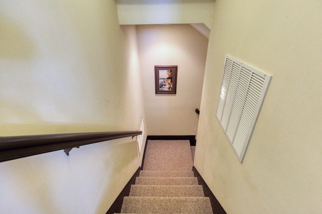 stairway featuring visible vents and a heating unit