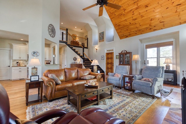 living room featuring light wood finished floors, stairway, wooden ceiling, high vaulted ceiling, and a ceiling fan