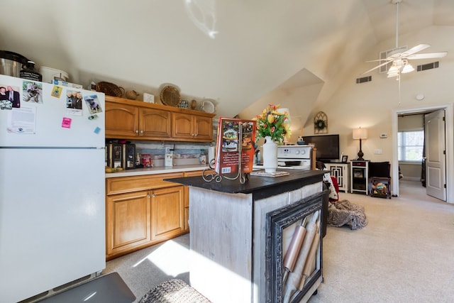 kitchen with visible vents, a center island, lofted ceiling, light carpet, and freestanding refrigerator