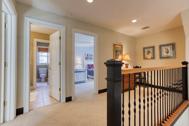 hallway with recessed lighting, visible vents, an upstairs landing, and light carpet