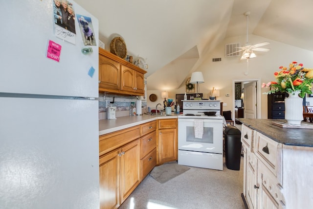 kitchen featuring white appliances, a peninsula, visible vents, and vaulted ceiling