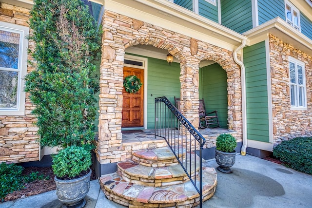 doorway to property featuring stone siding and a porch