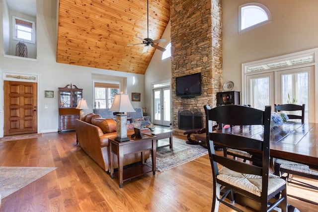 living room with baseboards, a fireplace, ceiling fan, french doors, and light wood-type flooring