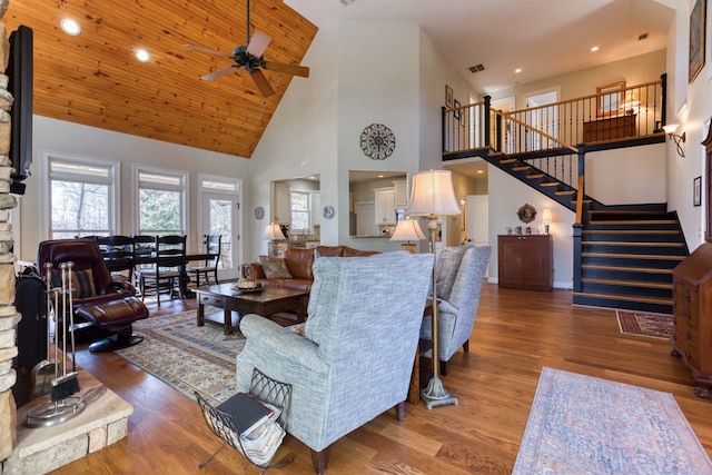 living area featuring visible vents, stairway, a high ceiling, wood finished floors, and a ceiling fan