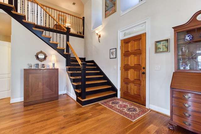 foyer with stairway, baseboards, and wood finished floors