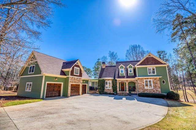 view of front of house featuring stone siding, driveway, a chimney, and a garage