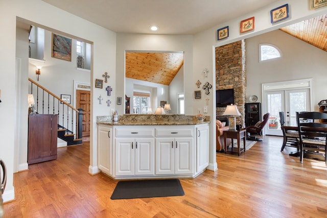 kitchen with high vaulted ceiling, light wood-style flooring, french doors, white cabinetry, and wooden ceiling