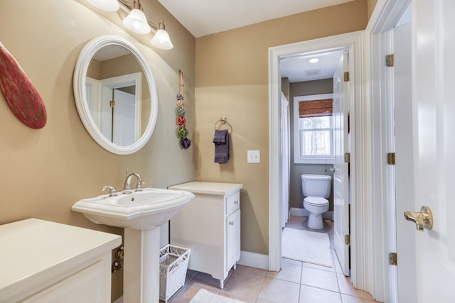 bathroom featuring tile patterned floors, toilet, baseboards, and a sink