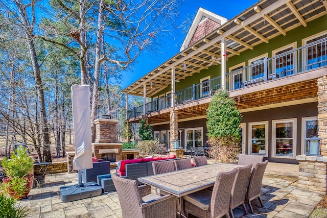 view of patio / terrace featuring an outdoor living space with a fireplace, outdoor dining space, and a balcony