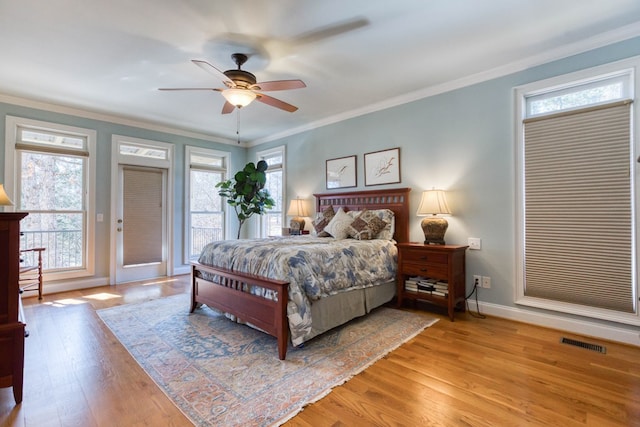 bedroom with visible vents, multiple windows, light wood-style floors, and ornamental molding