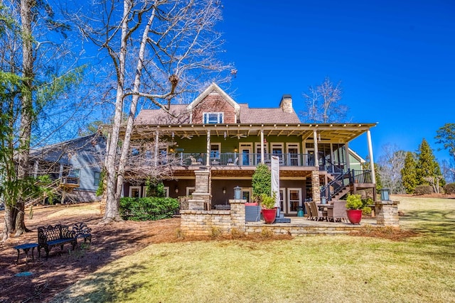 back of house featuring a patio area, stairway, a lawn, and a chimney