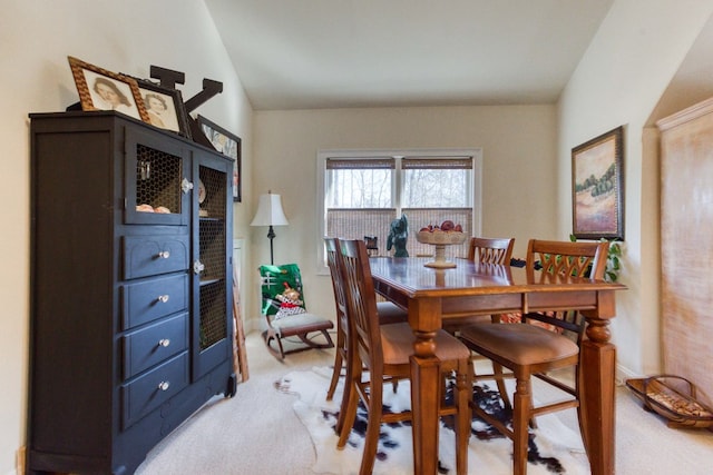 dining room with light colored carpet and vaulted ceiling