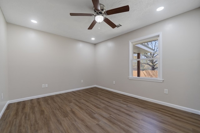 spare room featuring dark wood-style floors, visible vents, ceiling fan, and baseboards