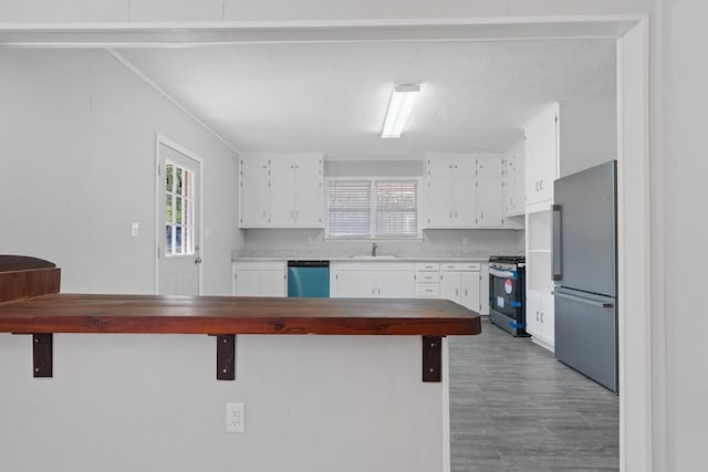 kitchen featuring sink, hardwood / wood-style flooring, appliances with stainless steel finishes, white cabinetry, and a kitchen breakfast bar