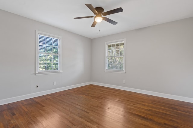 empty room featuring ceiling fan, a healthy amount of sunlight, and dark hardwood / wood-style flooring