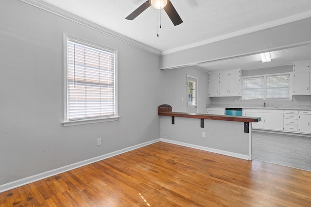 kitchen featuring white cabinetry, dishwasher, kitchen peninsula, light hardwood / wood-style floors, and a breakfast bar area