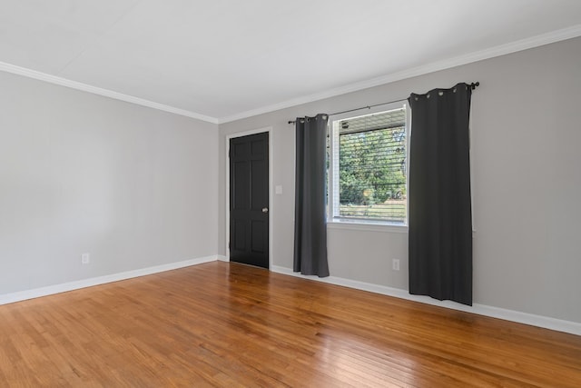 empty room featuring wood-type flooring and ornamental molding