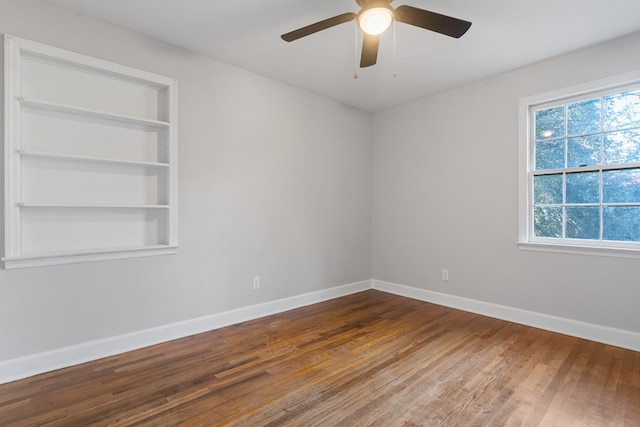 unfurnished room with built in shelves, ceiling fan, and wood-type flooring