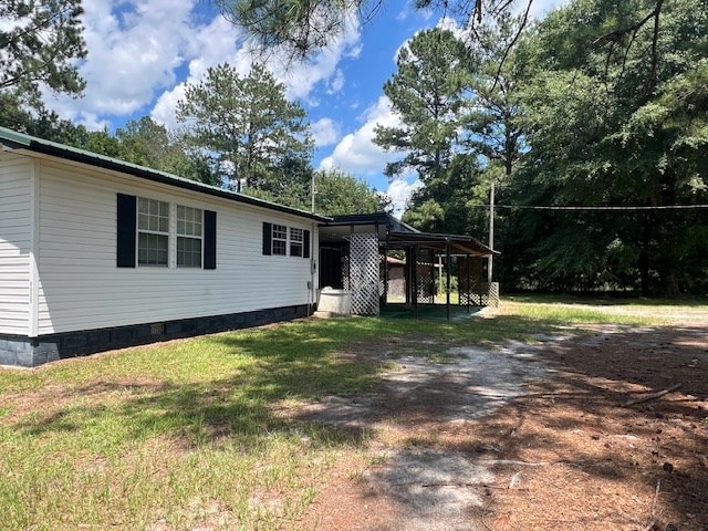 view of property exterior with a carport and a lawn