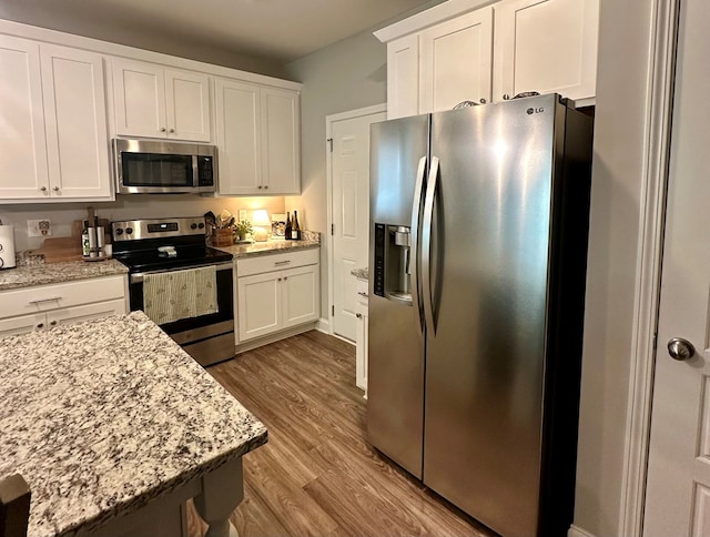 kitchen featuring light stone counters, appliances with stainless steel finishes, wood finished floors, and white cabinets